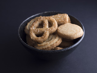 Danish butter cookies with vanilla wreaths (vanillekranse) and sugar pretzels (sukker kringler) in small black bowl isolated on black background