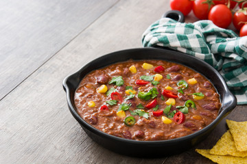 Traditional mexican tex mex chili con carne in a frying pan on wooden table
