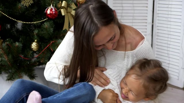 Mother tickling young daughter, both laughing and having a good time together