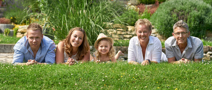 fr&ouml;hliche Familie liegt nebeneinander im Garten