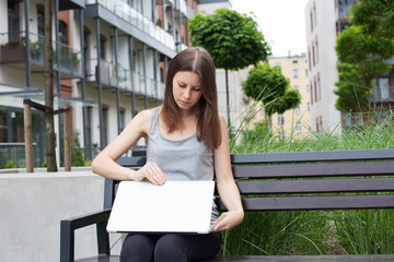 Fototapeta premium Young woman freelancer works with new silver laptop