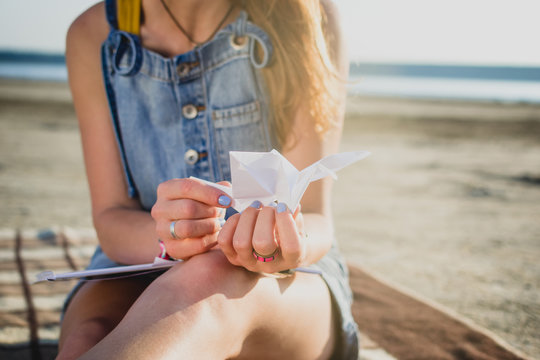 Young stylish hipster girl with origami on the beach, close up