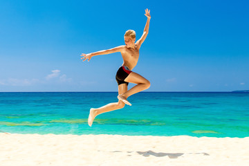 Happy teen boy having fun on the tropical beach. Summer vacation concept
