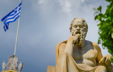 Close-up statue of the philosopher Socrates on the background of the Greek Flag