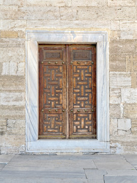 Wooden aged vaulted engraved door and exterior stone wall, Sultan Ahmet Mosque, Istanbul, Turkey	