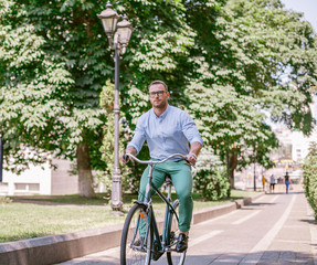 Businessman riding bicycle to work on urban street in morning. Lifestyle, transport, communication and people concept,