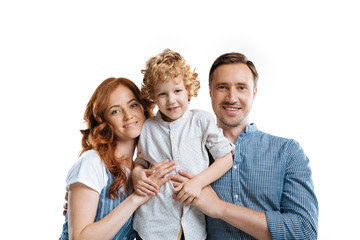 happy family smiling while embracing and looking at camera isolated on white