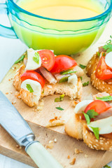Bruschetta with tomato, bacon and parsley matsarela in the process of eating, a cup of orange juice on a blue tablecloth. Close-up. Breakfast. Italian appetizer.