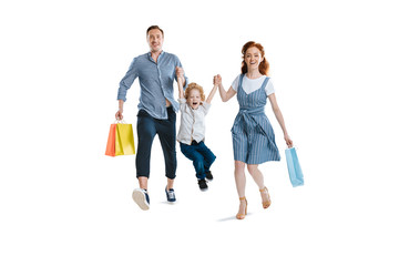 Obraz premium Happy young family with one child holding shopping bags and smiling at camera isolated on white