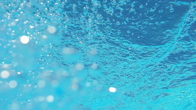 Bubbles rising to the surface. Slow motion. Air bubbles in clear blue water in pool (underwater shot), good for backgrounds
