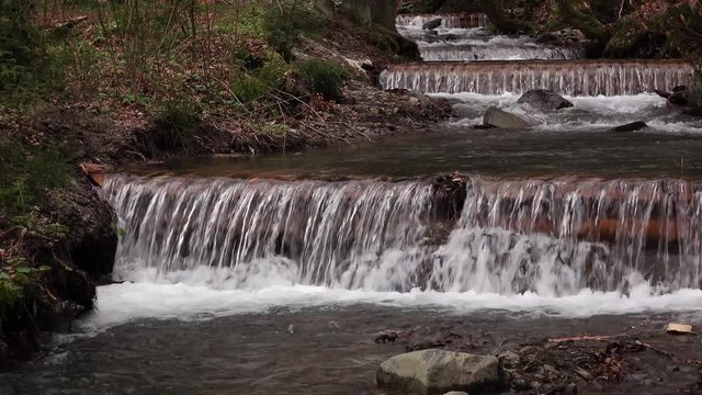 Mountain river with waterfalls and rapids flowing between rocky banks