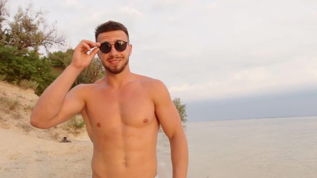 Young man standing in water by sea or ocean shore,