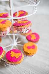 Cupcake colorati rosa e arancioni con decorazione farfalla, posizionati su giostra carillon