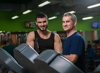 Senior man working with personal trainer in gym
