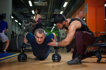 Senior man working with personal trainer in gym