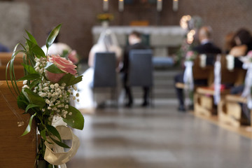 Blumenschmuck in der Kirche vor unscharfem Brautpaar