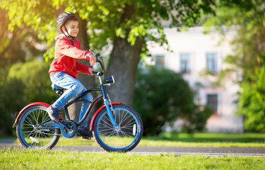 Fototapeta premium child on a bicycle at asphalt road in summer. Bike in the park