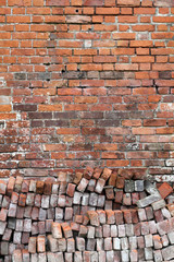 Old distressed red brick wall background with a pile of bricks in the foreground