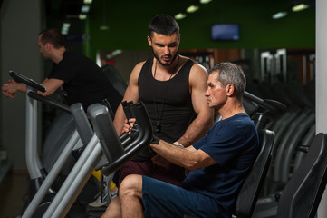 Fototapeta na wymiar Senior man exercising on machinein gym
