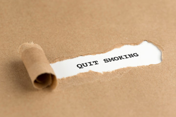 The text QUIT SMOKING appearing behind torn brown paper