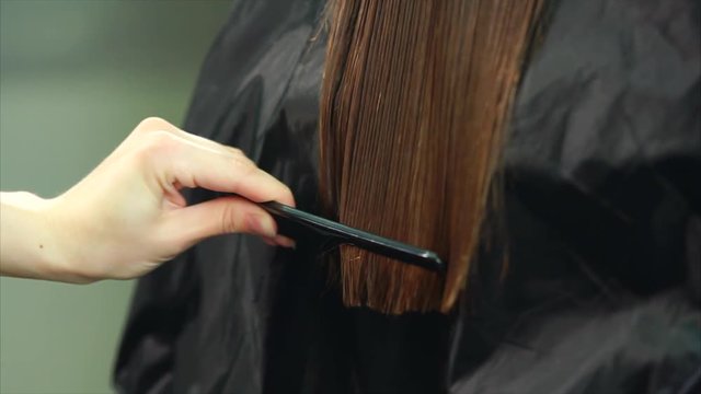 Close up shot of the process of cutting the split ends of the hair, the barber of the hand, who holds scissors and a comb for changing the hairstyle