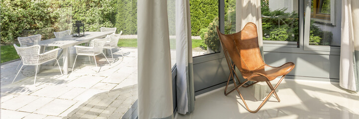 Orangery with a leather butterfly chair and view on the garden