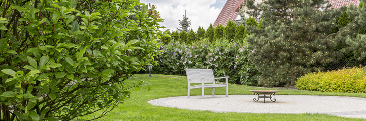 Well-kept home garden with a white bench