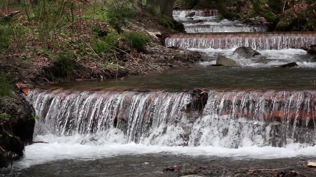 Mountain river with waterfalls and rapids, rocky banks. Slow motion