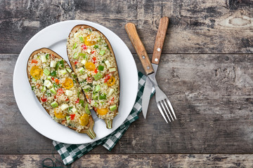 stuffed eggplant with quinoa and vegetables on wooden table - obrazy, fototapety, plakaty