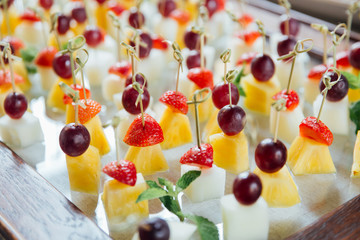 Set of delicious canapes with strawberry, pineapple, melon and grape.