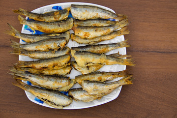 Fried baltic herring on a plate on wooden background