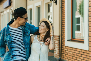 happy young hipster couple hugging while walking on the street