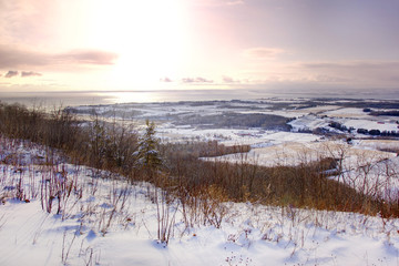 View from the top of a hill in winter with sunrise and snow 