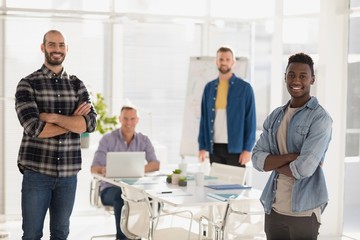 Male executives standing with arms crossed in the office