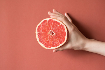Hands of a young woman holding a red grapefruit. healthy food concept