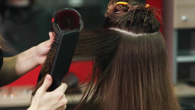 close up shot of the process of drying hair, the hairdresser divided the hair into two parts for convenience, warm air from the hair dryer and comb gently dried hair