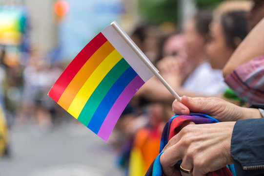 Gay Pride Parade spectator holding small gay rainbow flag during Toronto Pride Parade in 2017