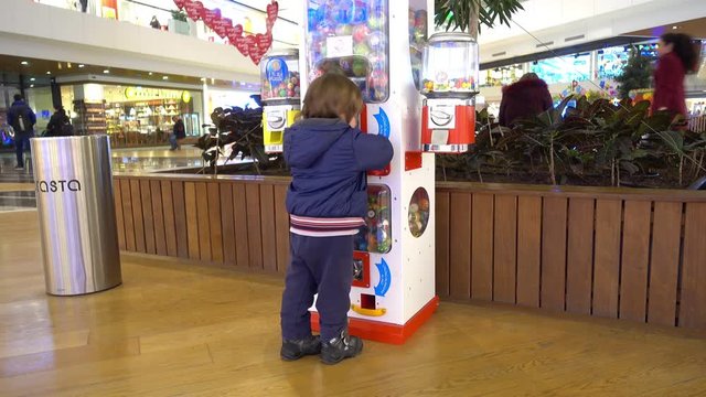 Fethiye, Turkey - 22th of December, 2016:  Erasta shopping center - 4K Child tries to break a candy slot machine in shopping center