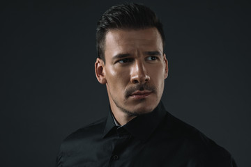 Fototapeta premium portrait of serious stylish man in black outfit looking away, isolated on grey