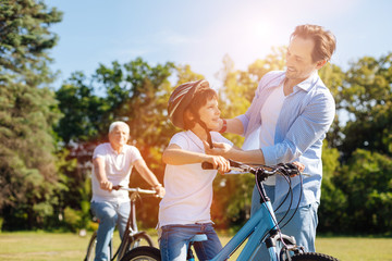 Caring nice dad putting on a helmet on his son