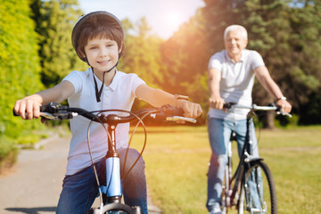 Obraz premium Young enthusiastic boy riding bicycles with his grandparent