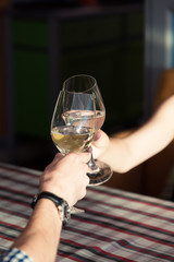 Young couple with glasses of white wine on a date in a cozy Italian restaurant. Leisure, drinks, people and holidays concept - happy man and woman clinking glasses.