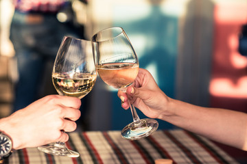 Young couple with glasses of white wine on a date in a cozy Italian restaurant. Leisure, drinks, people and holidays concept - happy man and woman clinking glasses.