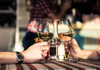 Young romantic couple with glasses of white wine on a date in a cozy Italian restaurant. Leisure, drinks, people and holidays concept - happy man and woman clinking glasses.
