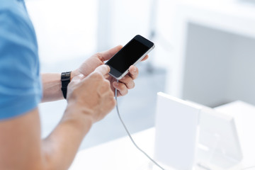 Scaled up shot of male hands touching smartphone screen