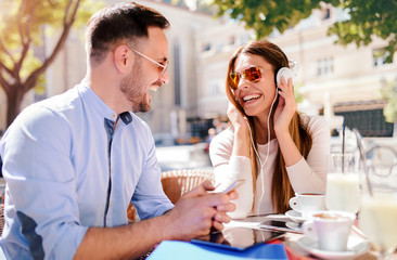 Dating. Young couple drinking coffee and having fun with mobile phone in the cafe. Love, dating, technology, lifestyle