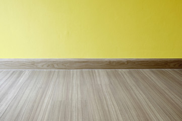 Empty room with oak wood laminate flooring and newly painted yellow wall in background