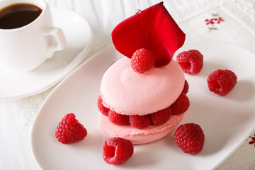 Delicious macaroon stuffed with raspberries and black coffee close-up. horizontal