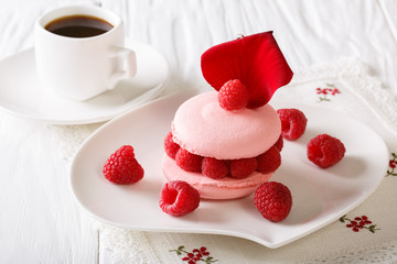 Pink macaroon stuffed with fresh raspberries, decorated with a rose petal and coffee close-up. horizontal