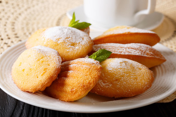 French cookies Madeleine and tea close-up on a lacy napkin. horizontal